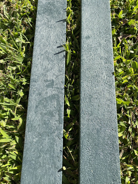 Dos tablas de madera plástica verde sobre el pasto, textura veteada